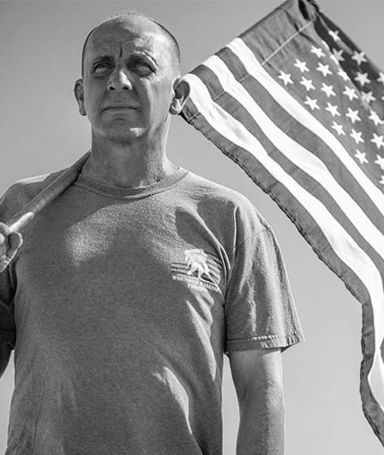 Wounded warrior James Rivera wearing a WWP t-shirt and holding an American flag.